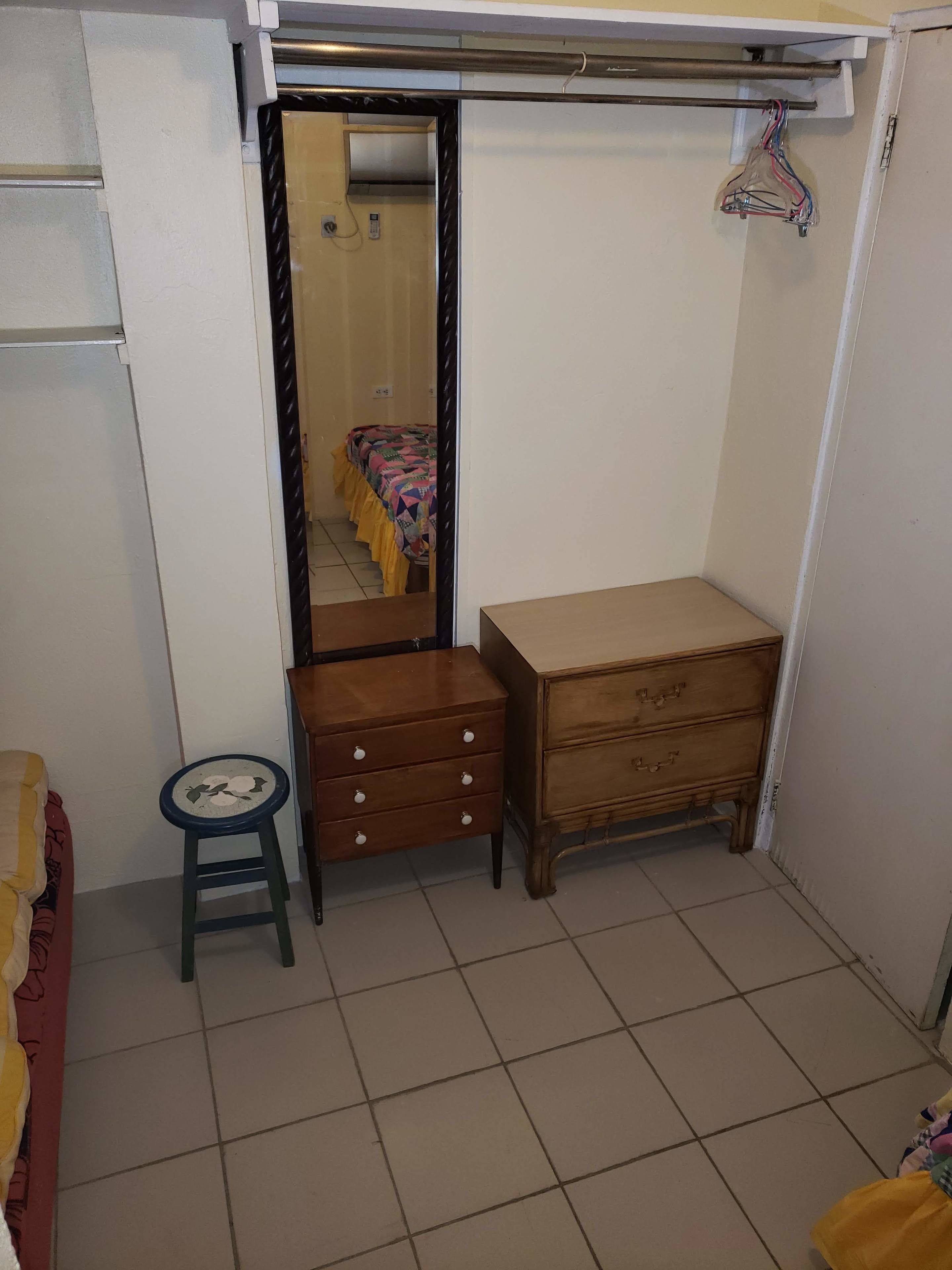 Una habitación pequeña y ordenada con un aparador de madera, un taburete y un espejo.