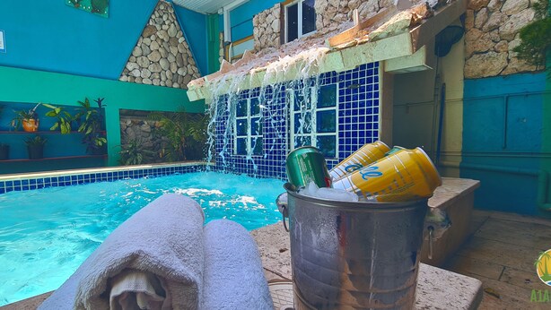 A pool area with a stone wall, potted plants, and a water feature. - A1 Apartments Aruba (Oranjestad)