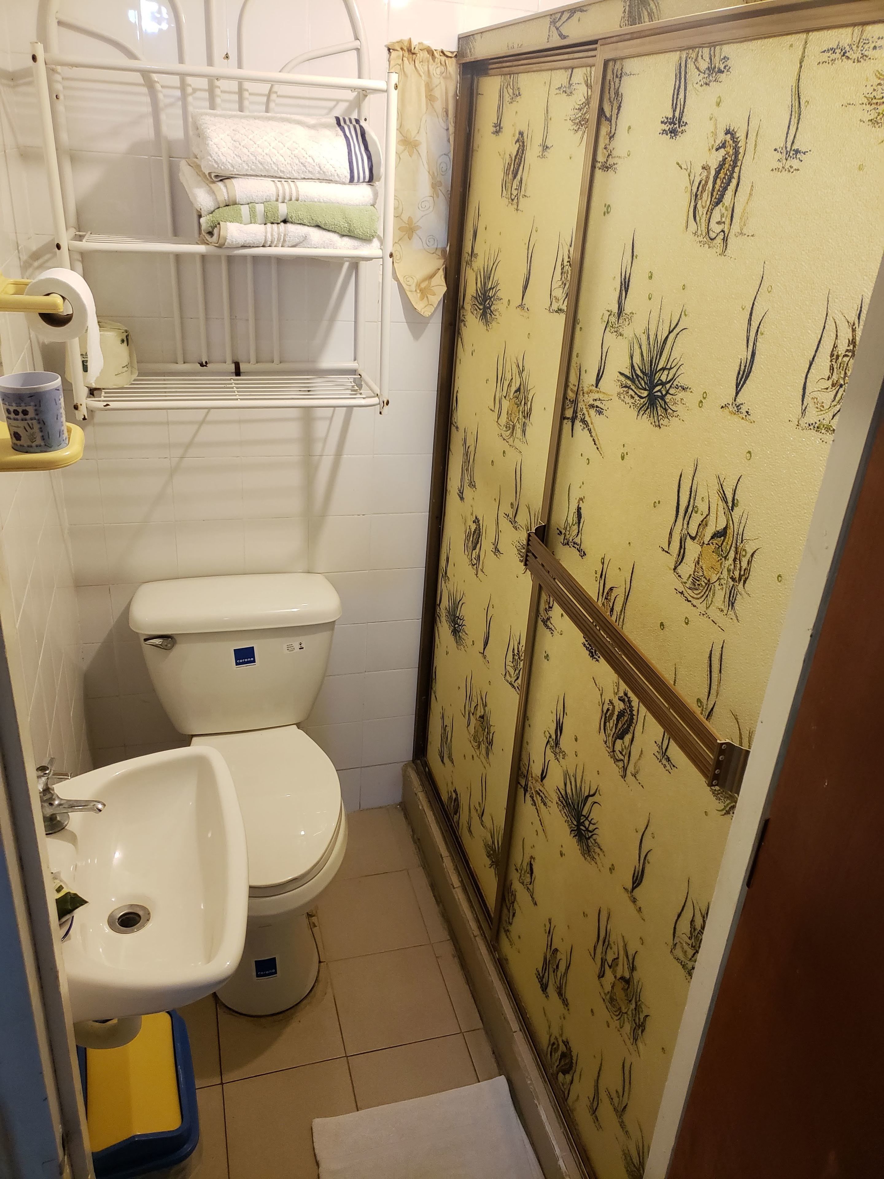 A bathroom with a toilet, sink, and shower area.