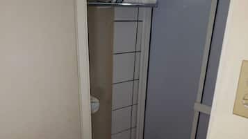Un baño pequeño con inodoro, repisas con toallas dobladas y zona de ducha.