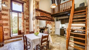 A rustic kitchen with exposed brick walls, wooden beams, and a dining area with a table set for two. - Casa Veneziana Chania, Casa Veneziana (Chania)