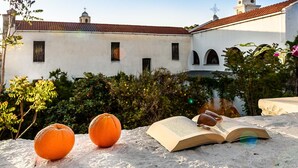 A stone table with an open book, two oranges, and a pair of sunglasses. - Casa Veneziana Chania, Casa Veneziana (Chania)