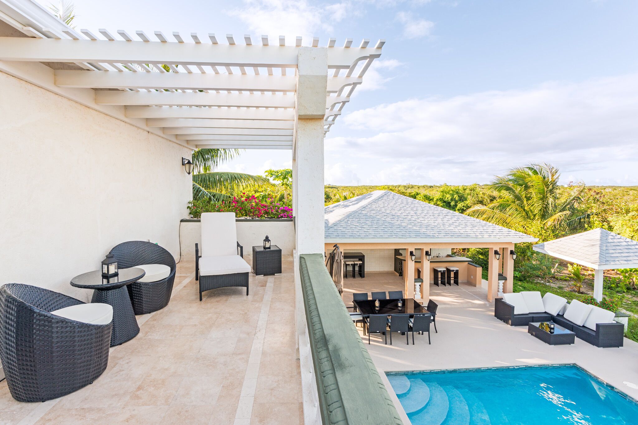 A covered outdoor area with a pool, seating, and a view of the landscape.