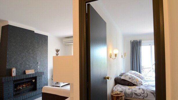 Une chambre à coucher avec un lit, une cheminée, une table de chevet et une fenêtre avec des rideaux.