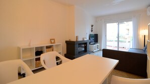 Un salon avec un canapé blanc, une table à manger, une cheminée et un téléviseur.