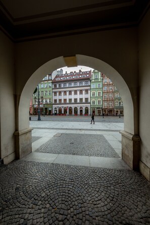 Un patio abierto con piso de adoquines y vista a edificios coloridos a través de un arco.