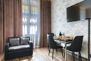 Una sala de estar moderna con un sofá, una mesa de comedor, sillas y un televisor de pantalla plana montado en la pared.