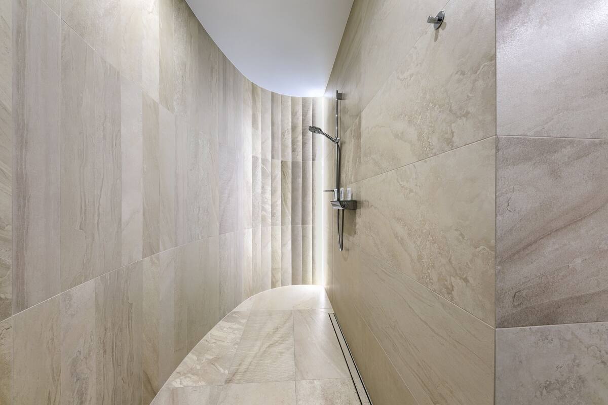 A modern bathroom with a curved shower area, tiled walls, and a visible showerhead.