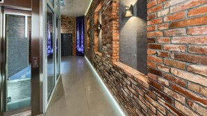 A modern hallway with a brick wall, glass doors, and a lighted path. - Aparthotel New Lux (Wroclaw)