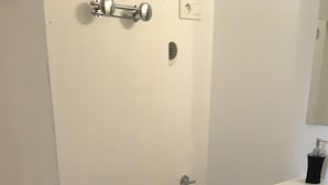 Un baño con inodoro, ducha, lavabo y un cubo de basura.