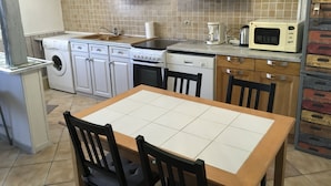 Cocina compacta con lavadora, lavavajillas, estufa, microondas y una mesa de comedor con sillas.