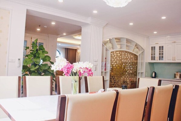 Enjoy meals in this stylish dining area with a table set for two, a vase with fresh flowers, and modern cabinetry.