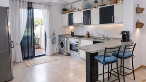 Een moderne keuken met een centraal eiland, inbouwapparatuur en een schuifdeur naar een balkon.