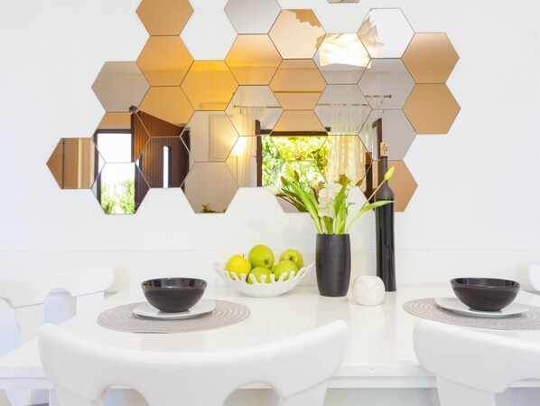 A modern dining area with a white table, hexagonal mirrors, and a vase with flowers. - Holiday home Mendy with Jacuzzi in the garden in a quiet location above Tučepi (Tučepi)