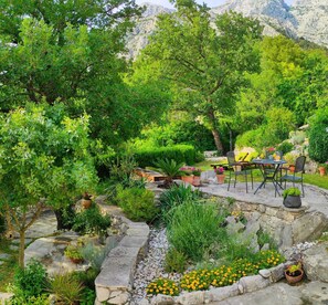 A garden patio with stone pathways, potted plants, and outdoor furniture. - Holiday home Mendy with Jacuzzi in the garden in a quiet location above Tučepi (Tučepi)