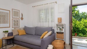 A modern living room with a grey sofa, a small side table, a woven rug, and a wicker basket. - Holiday home Mendy with Jacuzzi in the garden in a quiet location above Tučepi (Tučepi)