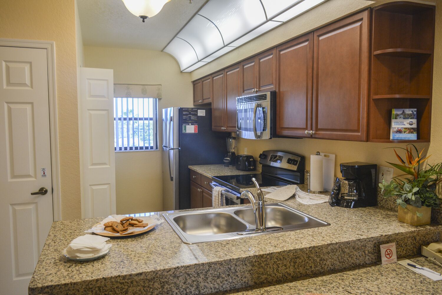 A kitchen with granite countertops, stainless steel appliances, wooden cabinets, and a built-in microwave.