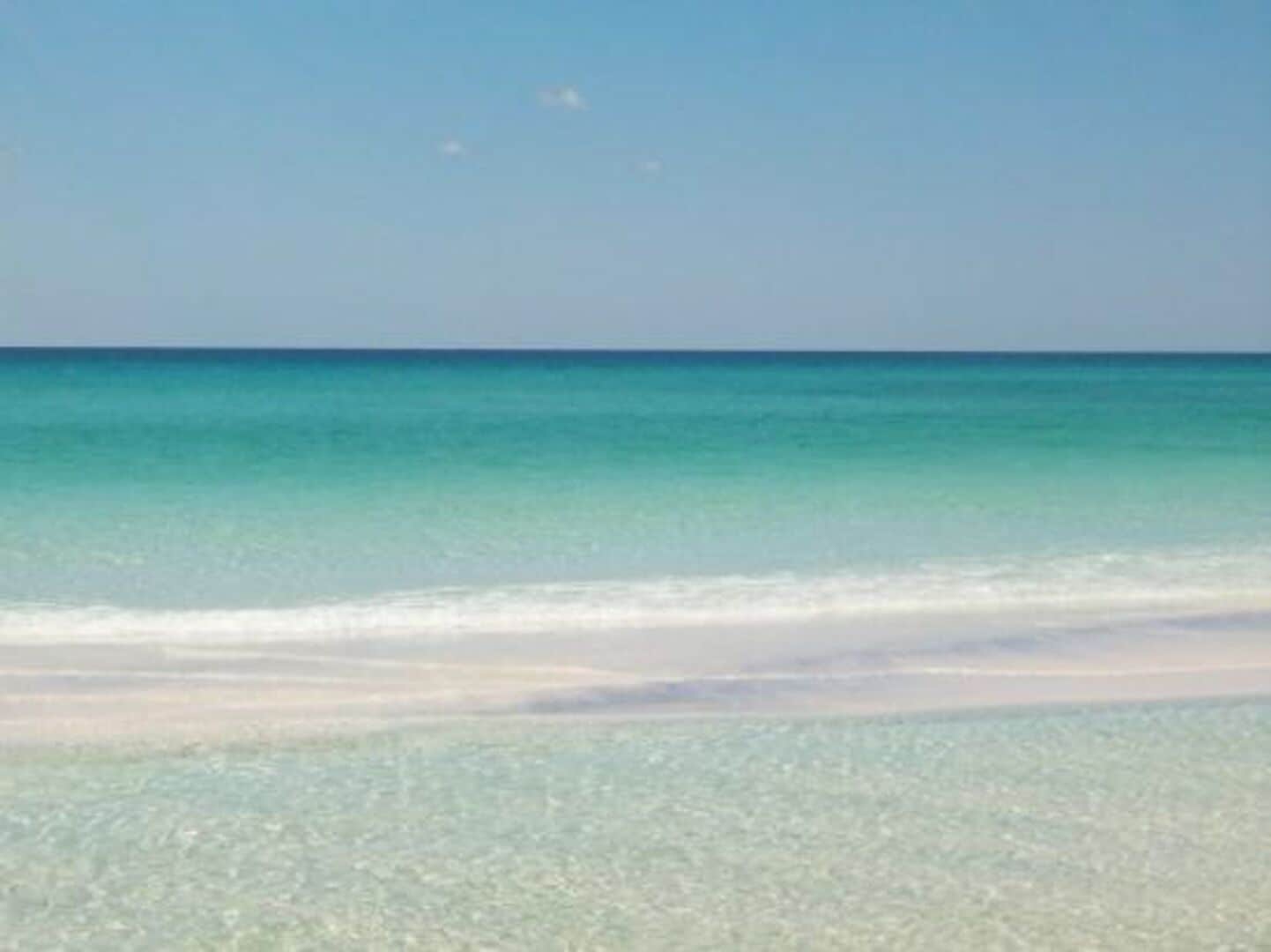 A beach with clear turquoise water and a sandy shore.
