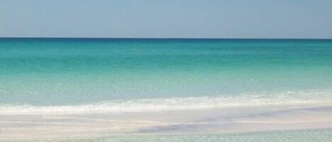 A beach with clear turquoise water and a sandy shore.