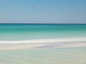 A beach with clear turquoise water and a sandy shore.