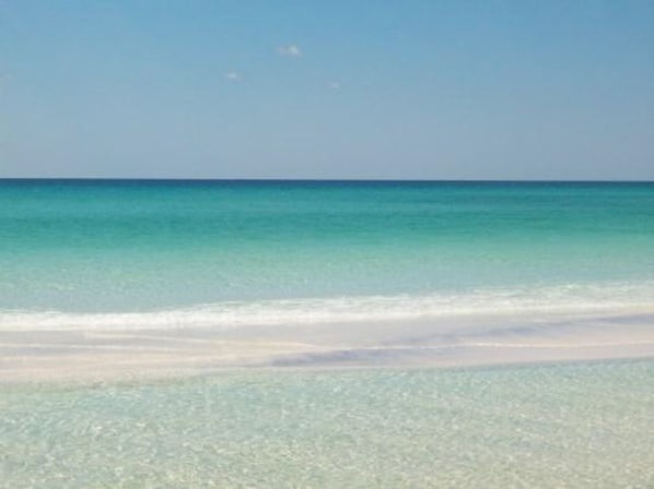 A beach with clear turquoise water and a sandy shore.
