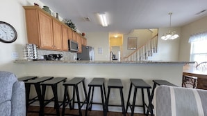 Una cocina con armarios de madera, una encimera y una zona con taburetes de bar.