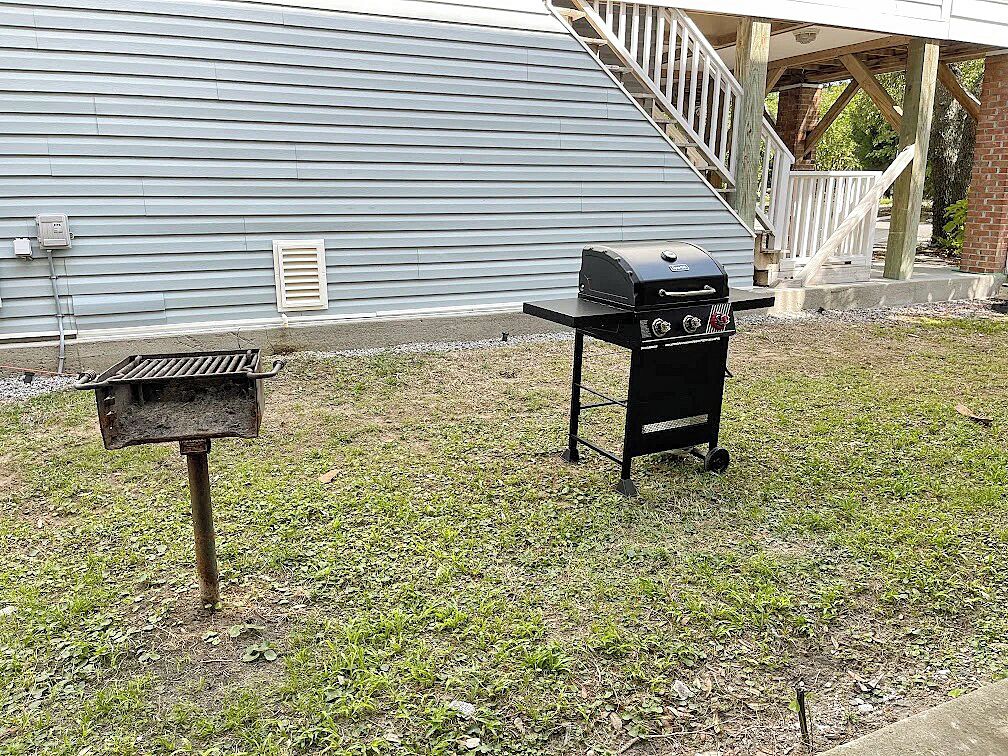 En baghave med grill, skraldespand og trappe op til en veranda.