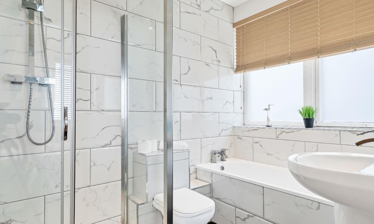 Een moderne badkamer met een douchecabine van glas, een toilet, een bad en een ruime wastafel.