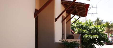 A building with a covered porch, a staircase, and a potted plant.