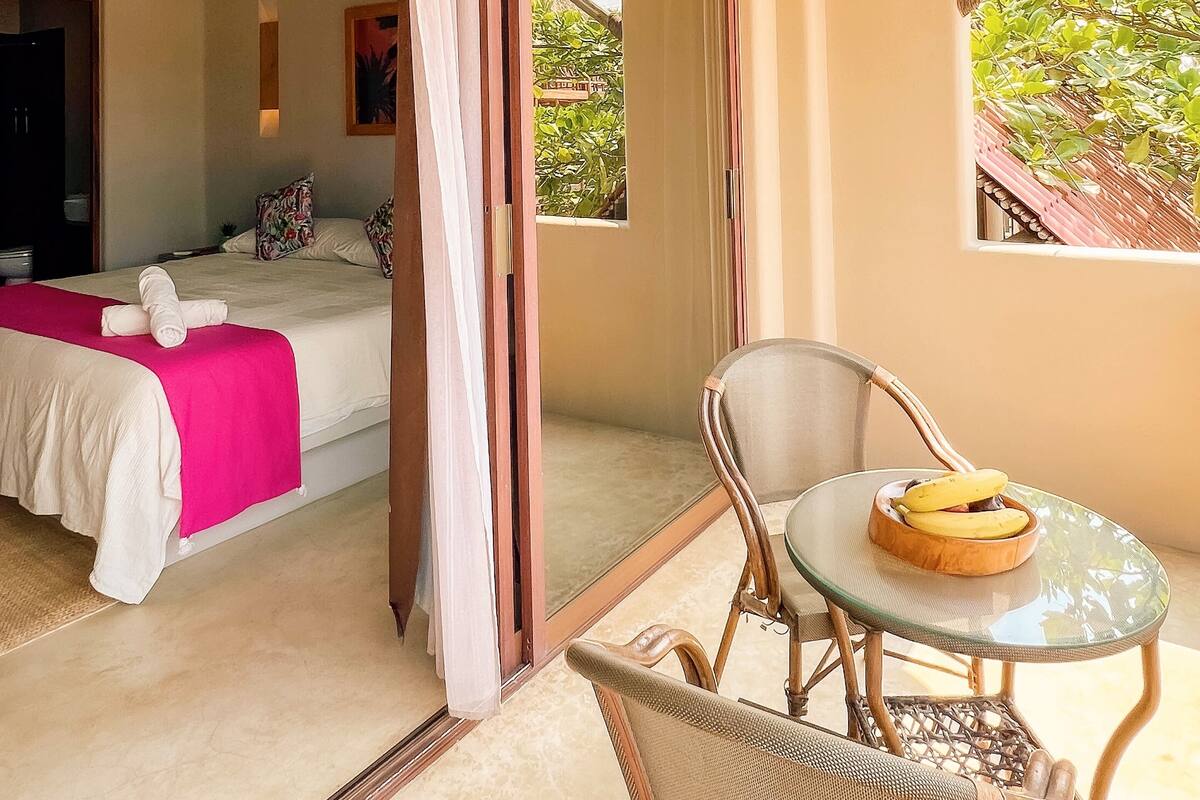 Una habitación con una cama, una mesa y un plátano, y una silla.