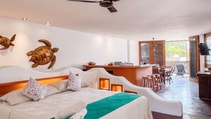 Ruime slaapkamer met een groot bed, een plafondventilator en uitzicht op het buitengebied.