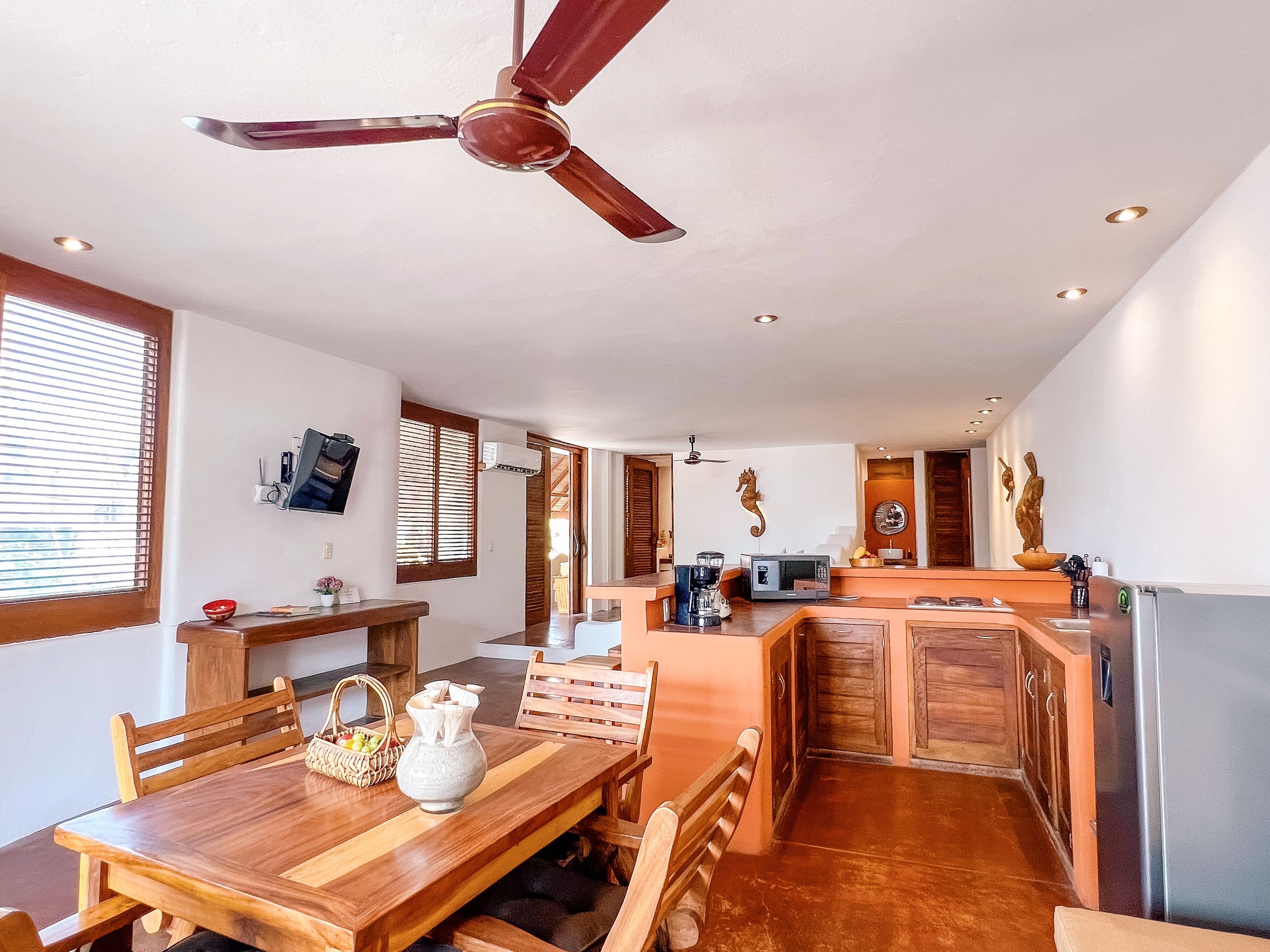 Une cuisine spacieuse dotée de meubles en bois, d’un îlot central et d’un coin repas avec une table et des chaises en bois.
