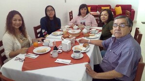 Un grupo de personas sentadas alrededor de una mesa con diferentes comidas y bebidas, indicando un ambiente para comer.