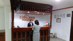 Mostrador de recepción del Hotel Explorer Deluxe, con diseño de madera y un cartel encima.