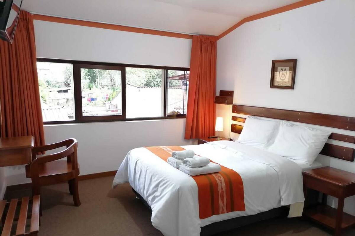 A hotel room with a bed, a desk, and a chair.