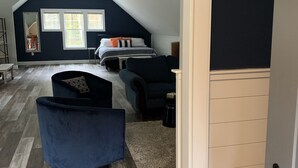 A spacious loft bedroom with a large bed, a seating area, and a view of the outdoors. - Goose Rocks Retreat - relax, refresh, recharge  (Kennebunkport)