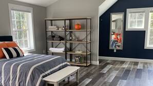 A bedroom with a bed, a bench, a wooden floor, a bookshelf, and a window. - Goose Rocks Retreat - relax, refresh, recharge  (Kennebunkport)