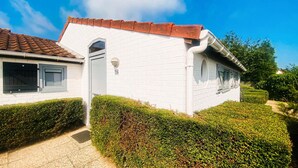 A white building with a red-tiled roof, a number '156' on the door, and a small window.