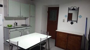 Een kleine keuken met een eettafel, stoelen en kastjes.