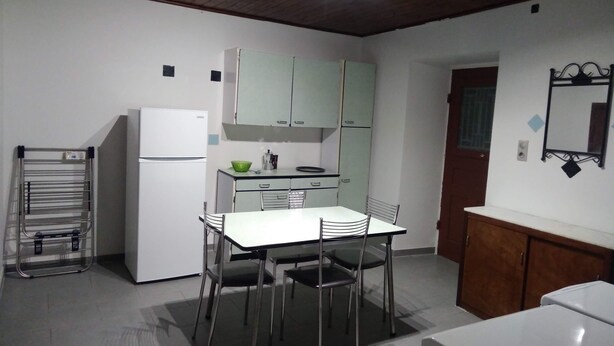 Een compacte keuken met een koelkast, een spoelbak en een eettafel met stoelen. Er is een houten plafond en een spiegel aan de muur.