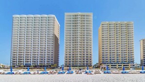 Three high-rise hotels with balconies, a sandy beach, and blue umbrellas. - “Barefoot Bliss” - Two GulfFront Masters w/balcony (Panama City Beach)