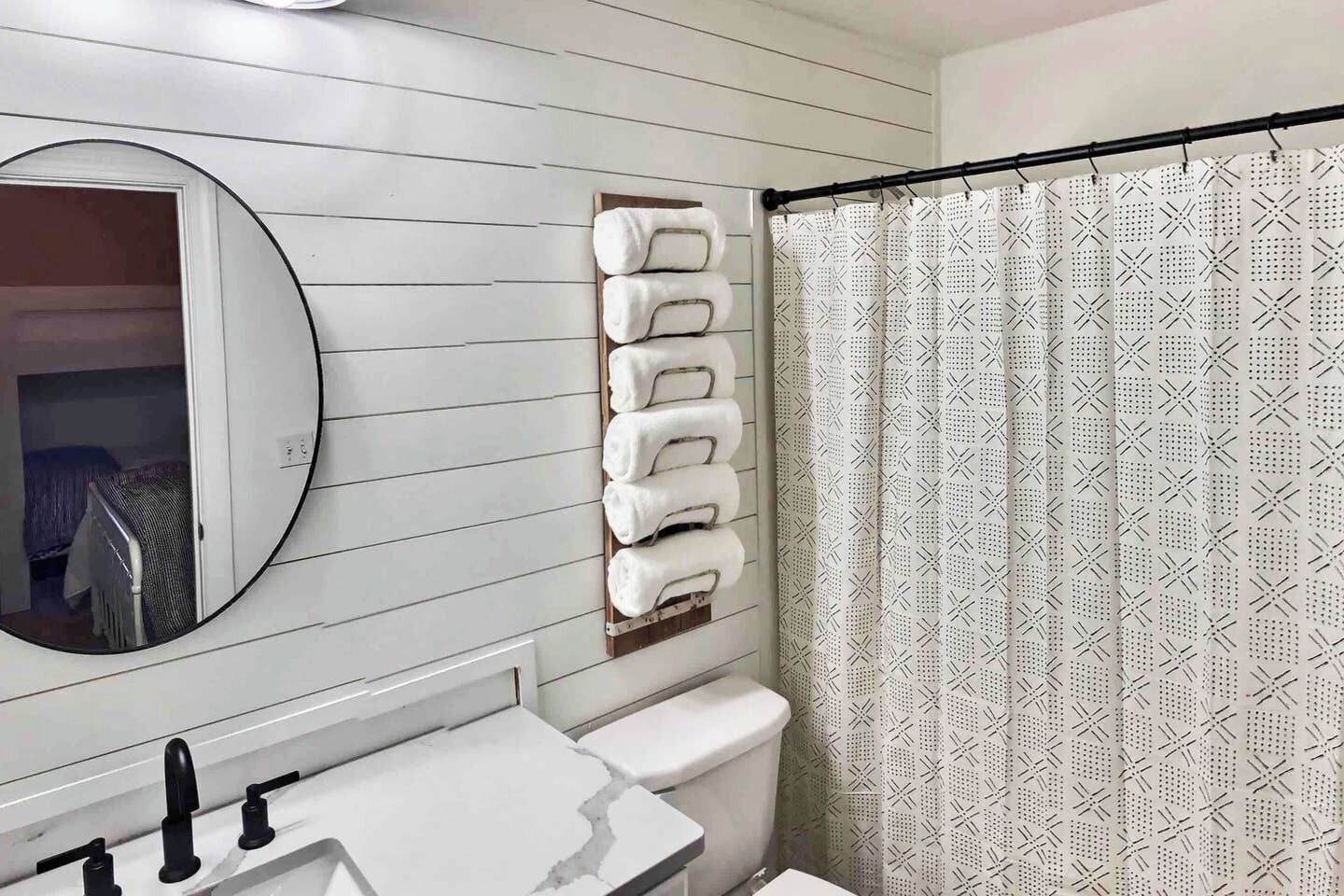 Un baño con tocador blanco, espejo y barra para toallas.