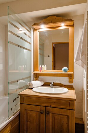 Une salle de bain avec un meuble-lavabo en bois, une cabine de douche en verre et un miroir au-dessus du lavabo.
