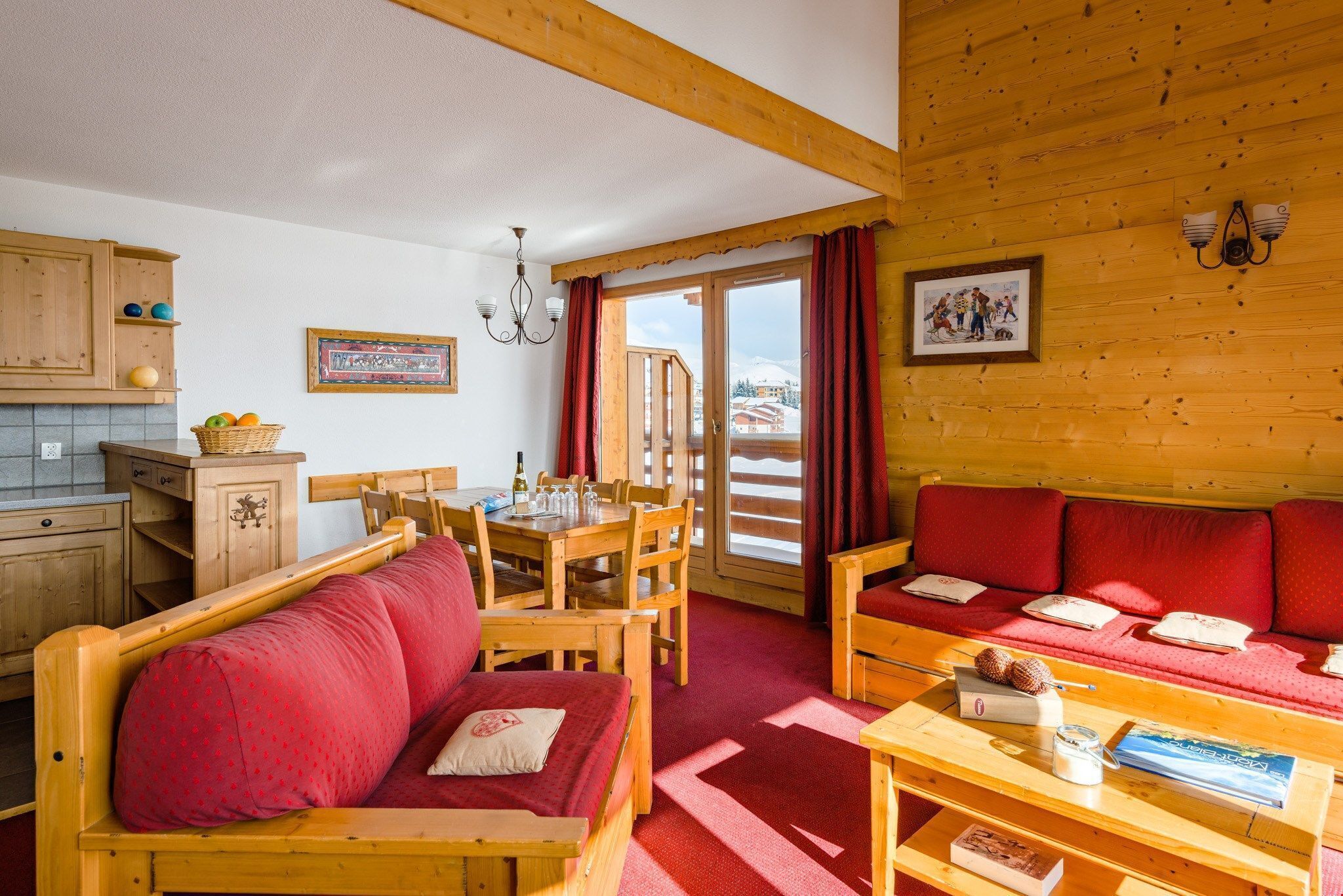 A cozy wooden cabin with a dining area, a sofa, and a table with books and a candle.
