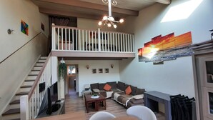 A spacious living area with a high ceiling, a balcony, a dining table, and a fireplace. - 70 m² modern house, 650 m from the beach, rated 3 stars. 2027 RATES OK (Fleury)