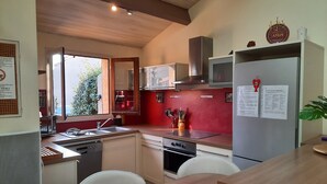 A modern kitchen with a wooden countertop, a built-in oven, a stainless steel sink, and a refrigerator with papers attached. - 70 m² modern house, 650 m from the beach, rated 3 stars. 2027 RATES OK (Fleury)