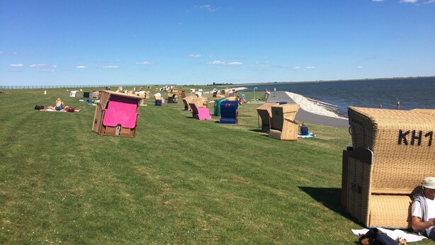 A grassy area with several beach chairs and a wicker basket labeled "KHT".