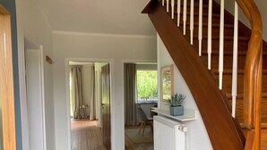 A staircase leading to a room with a desk and chair, a radiator, and a view of a garden through a window.
