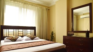 A hotel room with a bed, a dresser, a mirror, and a window with curtains. - Charming Downtown Apartment in the heart of Cairo (cairo)