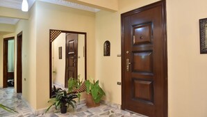 A hallway with a wooden door, a mirror, and potted plants. - Charming Downtown Apartment in the heart of Cairo (cairo)